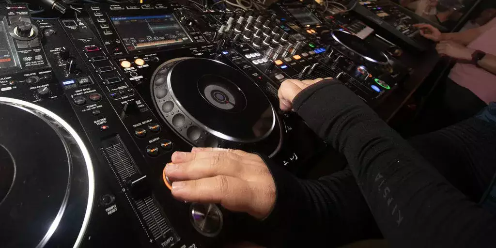 Mains de DJ réglant les platines et la table de mixage
