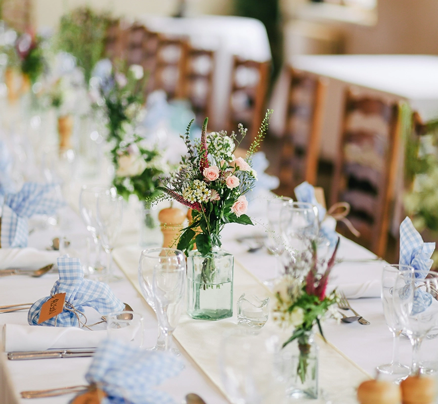 Table de mariage dressée en décoration champêtre, fleurs et vaisselle sur nappe de lin.