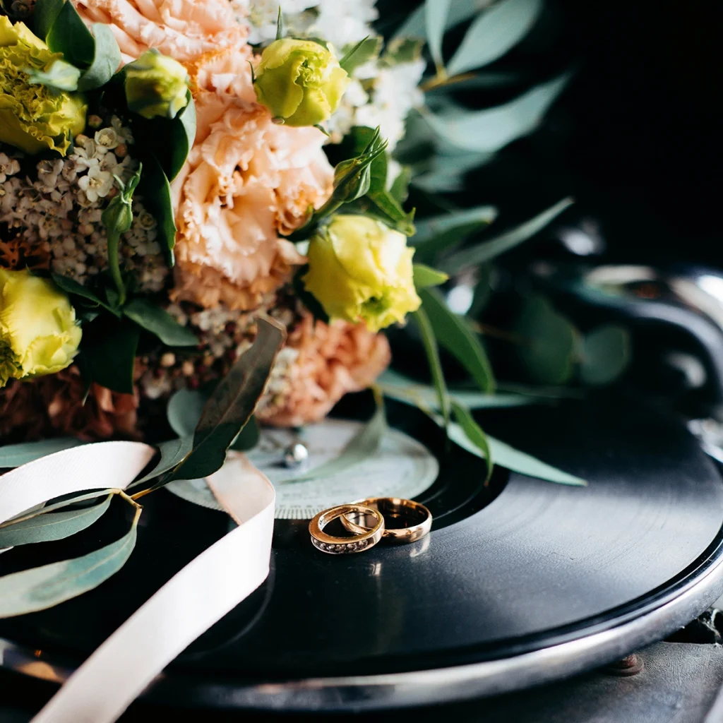 Deux alliances et un bouquet de mariée posés sur une platine.
